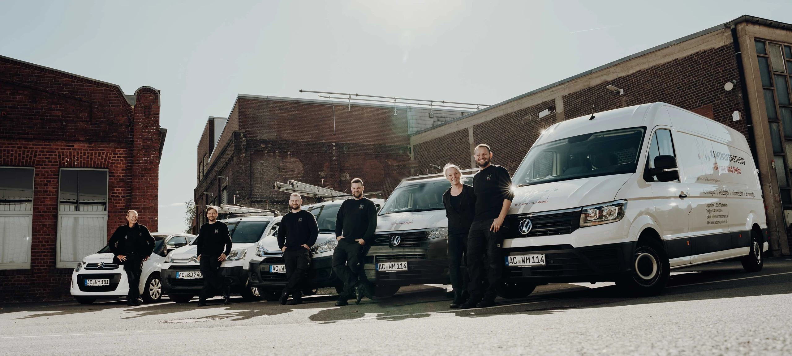 Das Team vor den Firmenfahrzeugen