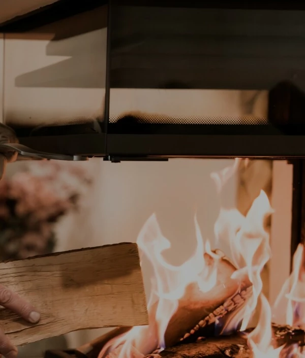 Mann legt Holz in den Ofen